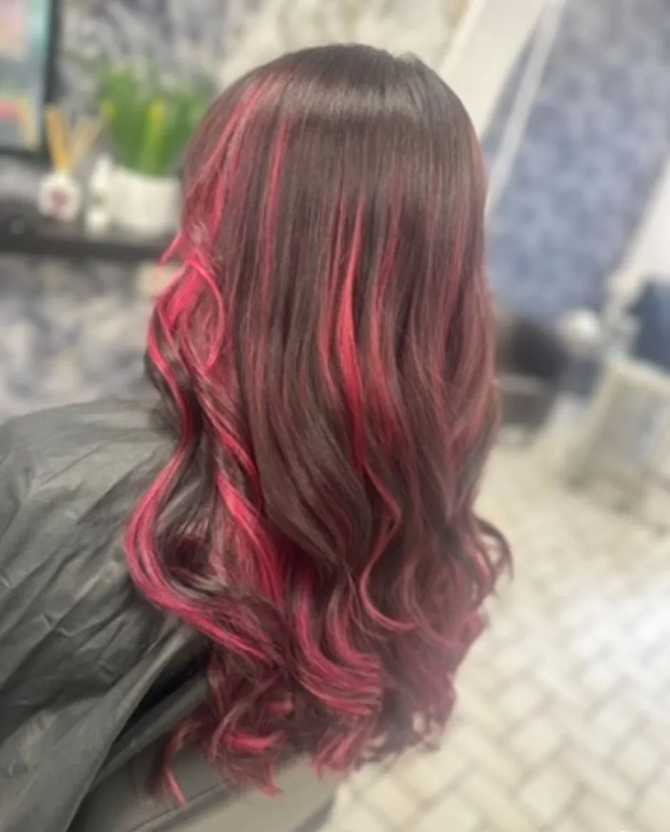 Dark brunette with vivid pink highlights and bouncy curled ends